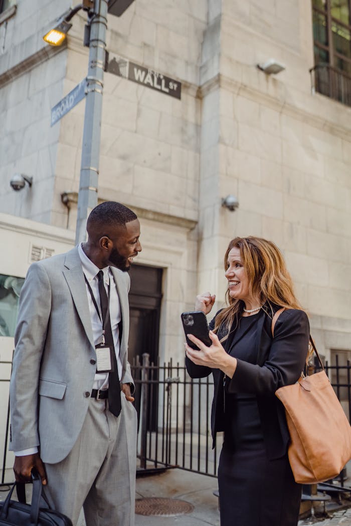 Two business professionals conversing happily on Wall Street, New York City.